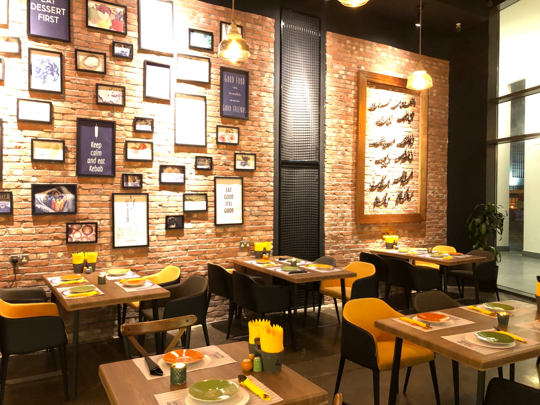 The gallery-wall dining room — brick, calligraphy and yellow chairs